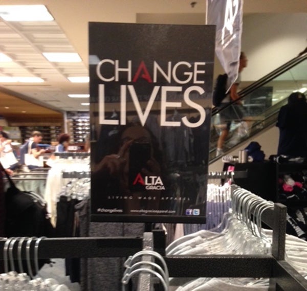 A sign that says Change Lives Alta Gracia with rows of apparel in the Georgetown bookstore