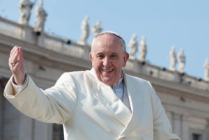 Pope Francis with a raised arm outside a building