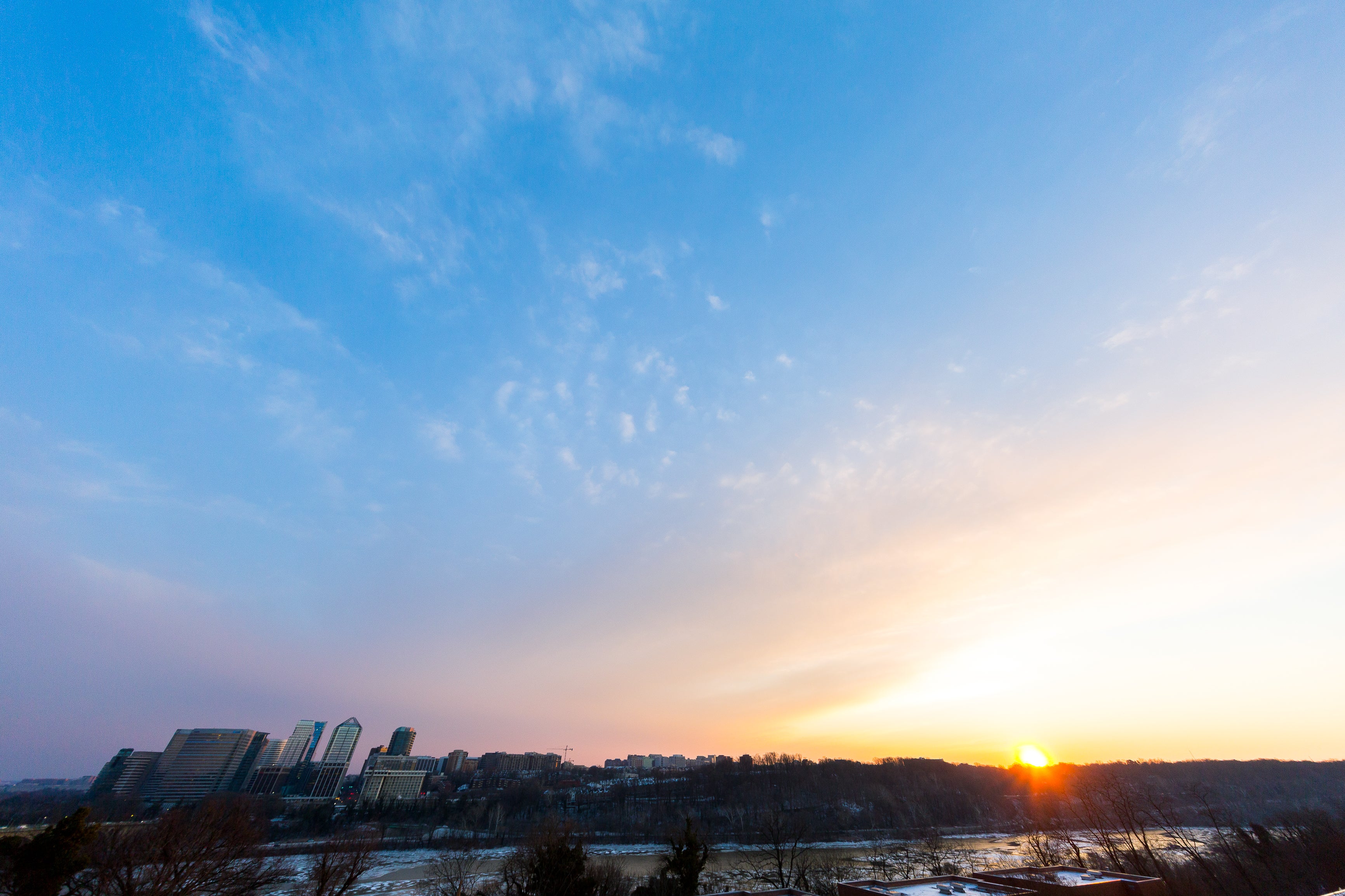 Photo shows the sun setting over a snowy scene on the Potomac River.