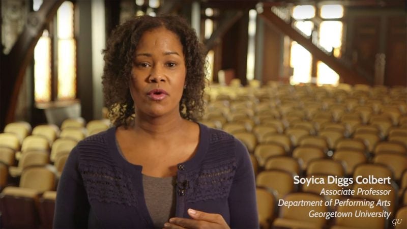 Soyica Colbert stands on stage with theater seats in the background.