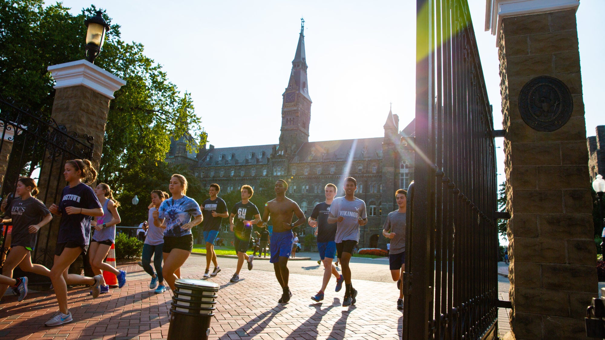 A group of runners running away from Georgetown&#039;s campus past the front gates.