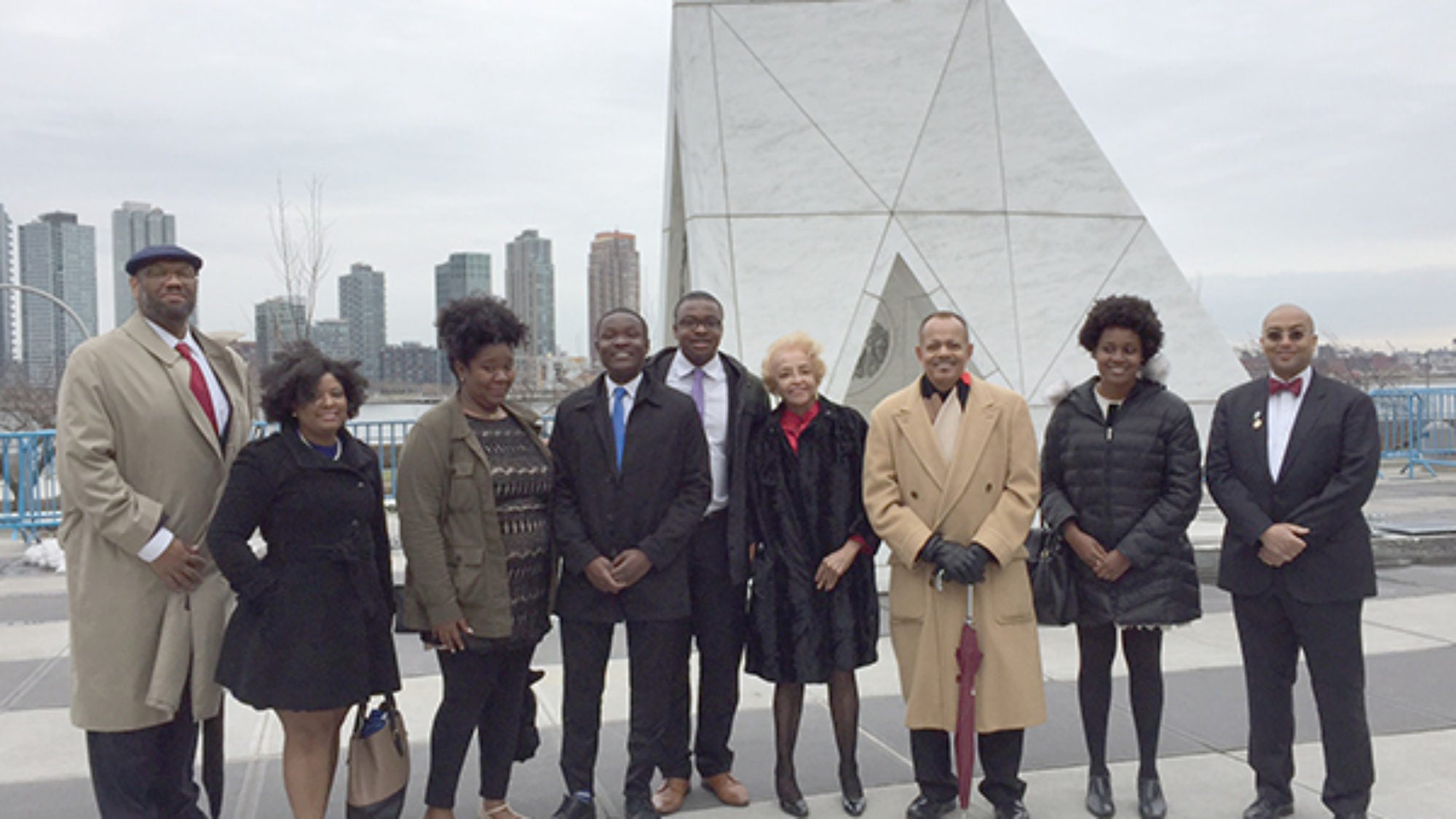 Descendants and other members of the Georgetown community stand before a sculpture at the United Nations in New York