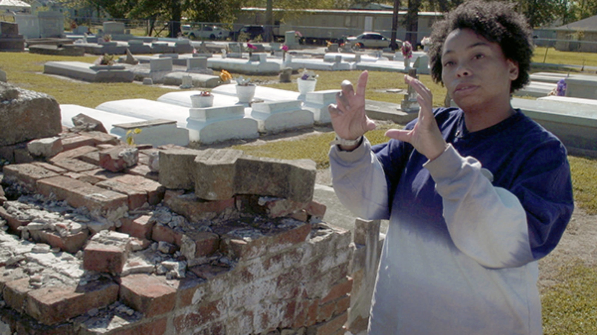 Jessica Tilson gesturing with hands in a cemetery where her ancestors are buried