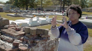 Jessica Tilson gesturing with hands in a cemetery where her ancestors are buried