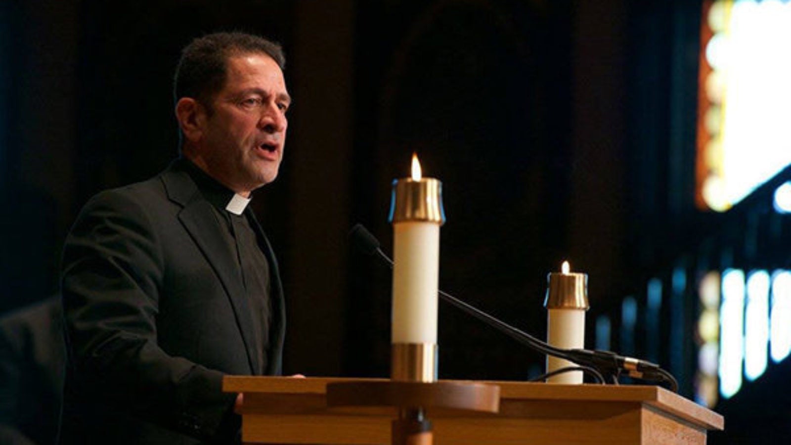 Rev. Timothy Kesicki, S.J.,standing in front of table with candles