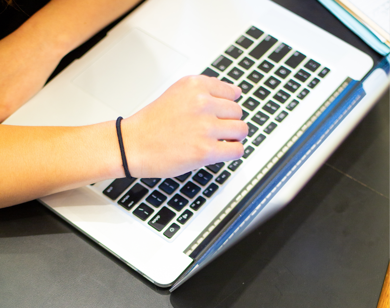 A hand is seen hovering above a keyboard.