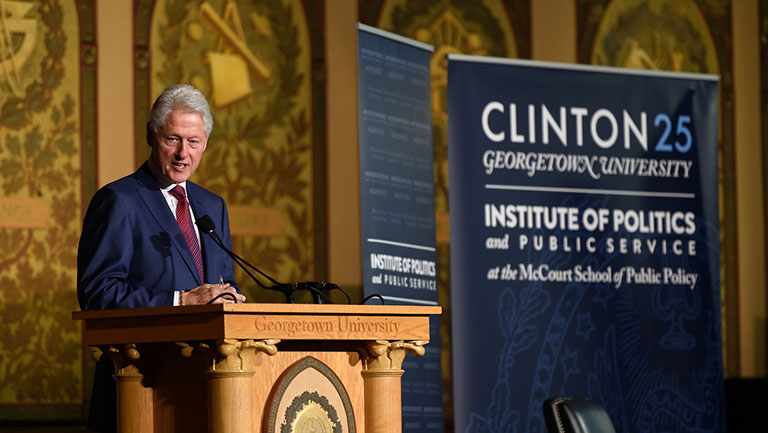 Former President William J. Clinton speaking into a microphone on stage.