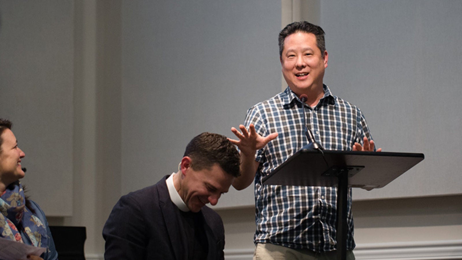 Steve Park at a podium with two people sitting and laughing.