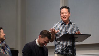 Steve Park at a podium with two people sitting and laughing.