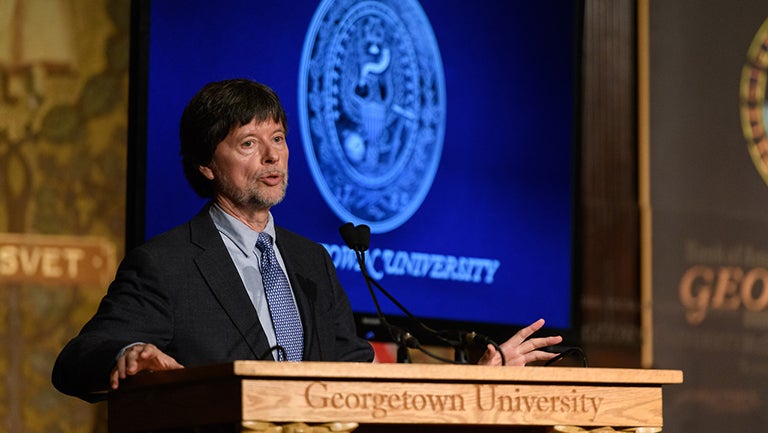 Ken Burns speaking at podium with Georgetown University banner and seal