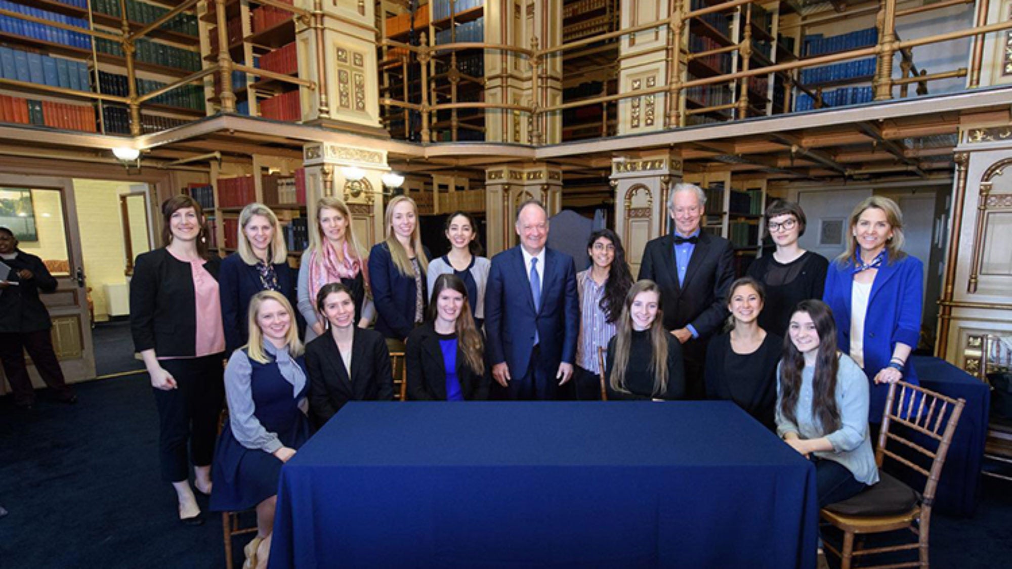 Bill McDonough and John J. DeGioia stand around a table with students and administrators