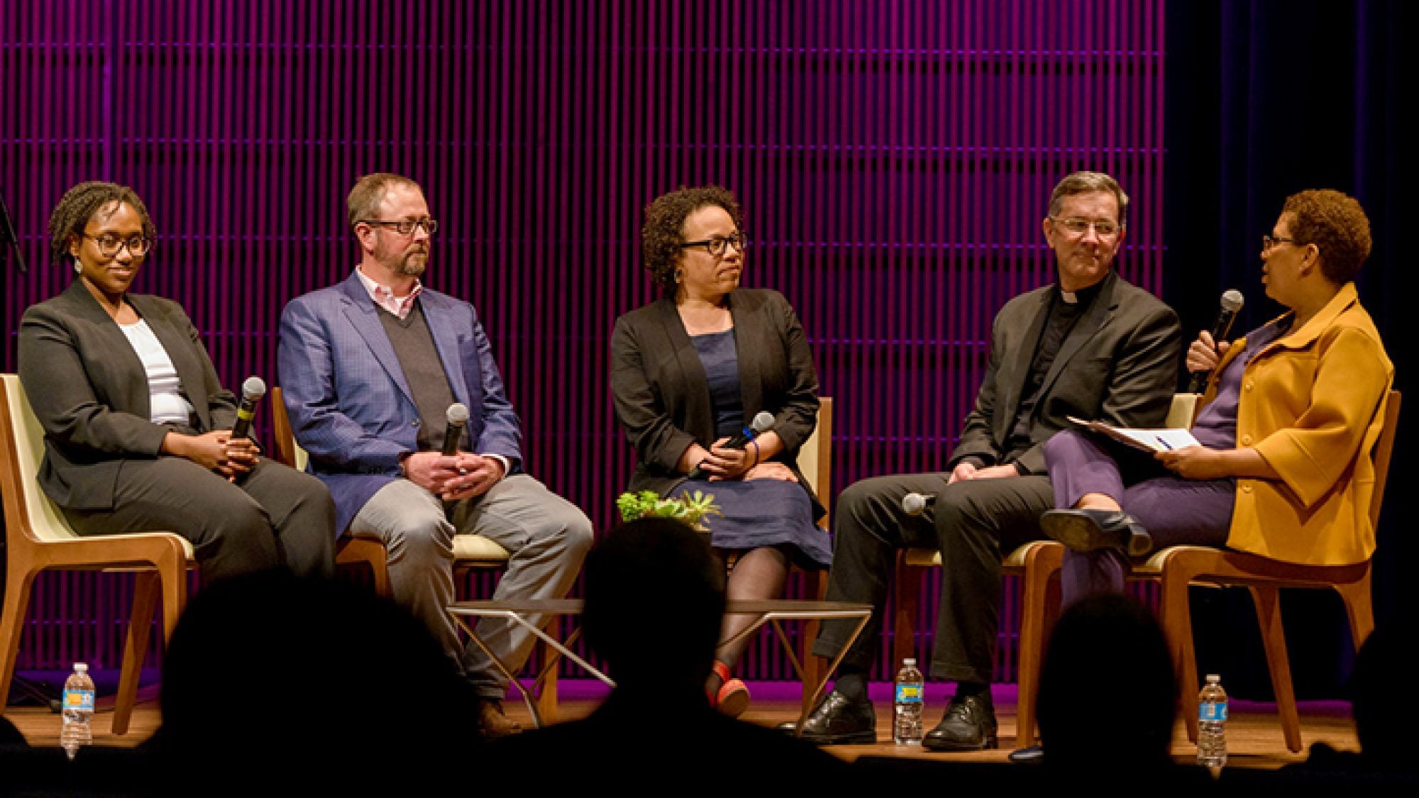 Panelists sit on a stage