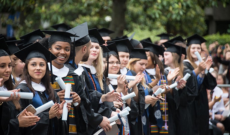 Students in cap and gowns holding diplomas