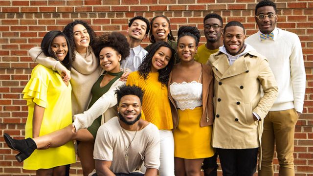 Members of Black Student Alliance smiling in front of a brick wall.