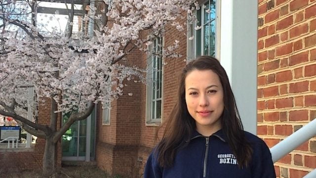 Hana Burkly outside in front of a building and a cherry tree