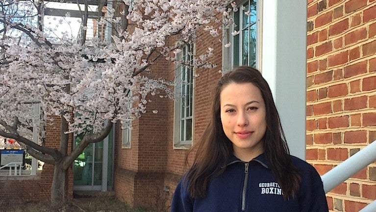 Hana Burkly outside in front of a building and a cherry tree