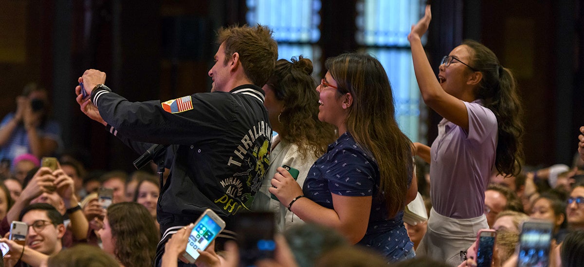 Bradley Cooper bere selfie se skupinou studentů, stojící v uličce v Gaston Hall.