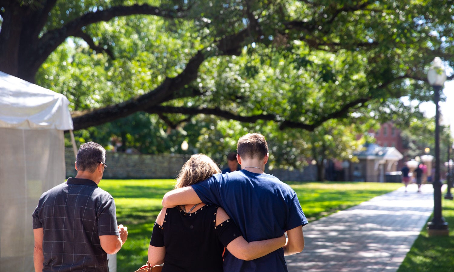 A mother and son walk on the lawn arm in arm