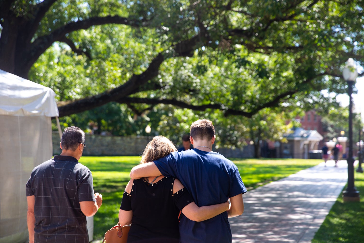 A mother and son walk on the lawn arm in arm