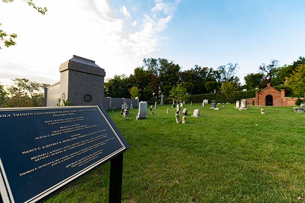 Plaque at Holy Rood Cemetery describing the cemetery with headstones in the background