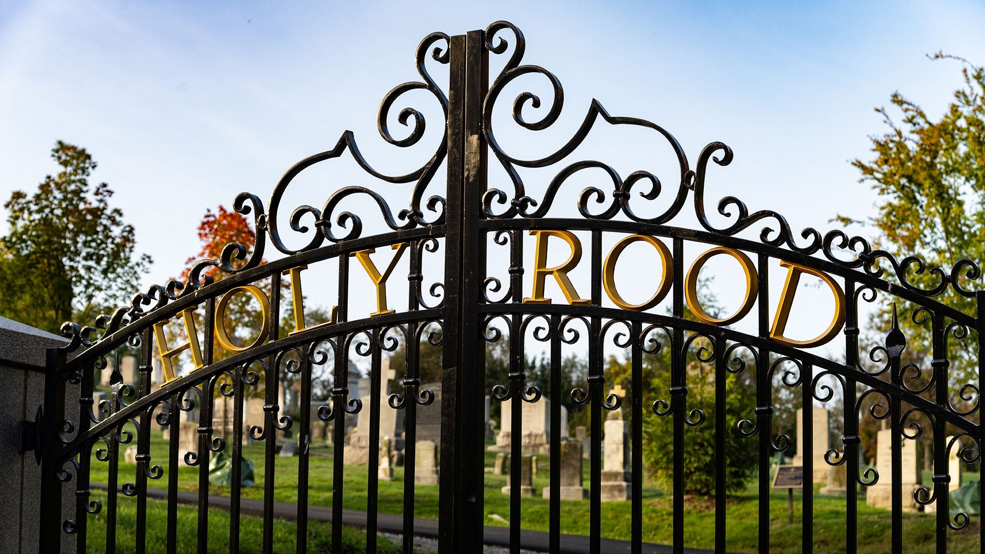 Holy Rood Cemetery&#039;s iron gate with tombstones in the background