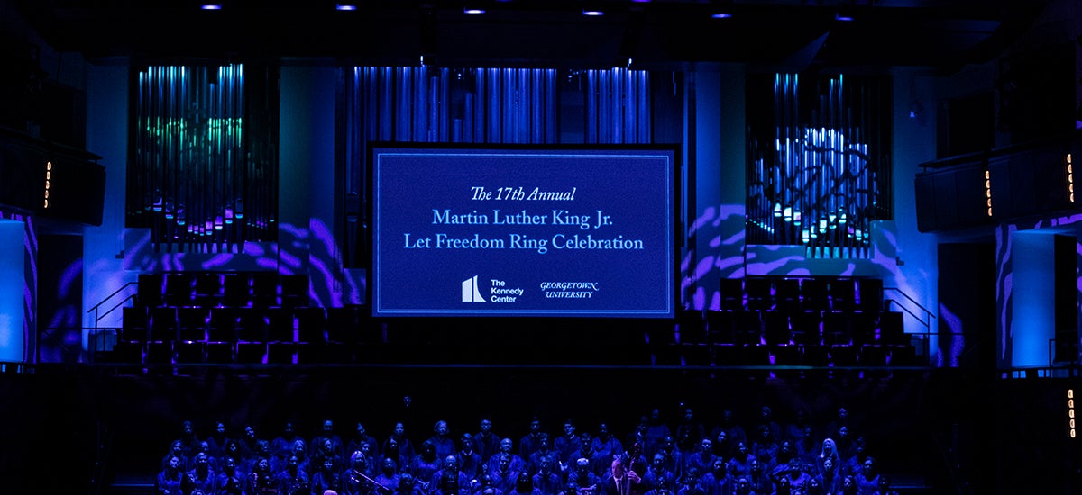 A dim blue-lit stage features a screen with The 17th Annual Martin Luther Ling Jr. Let Freedom Ring Celebrration