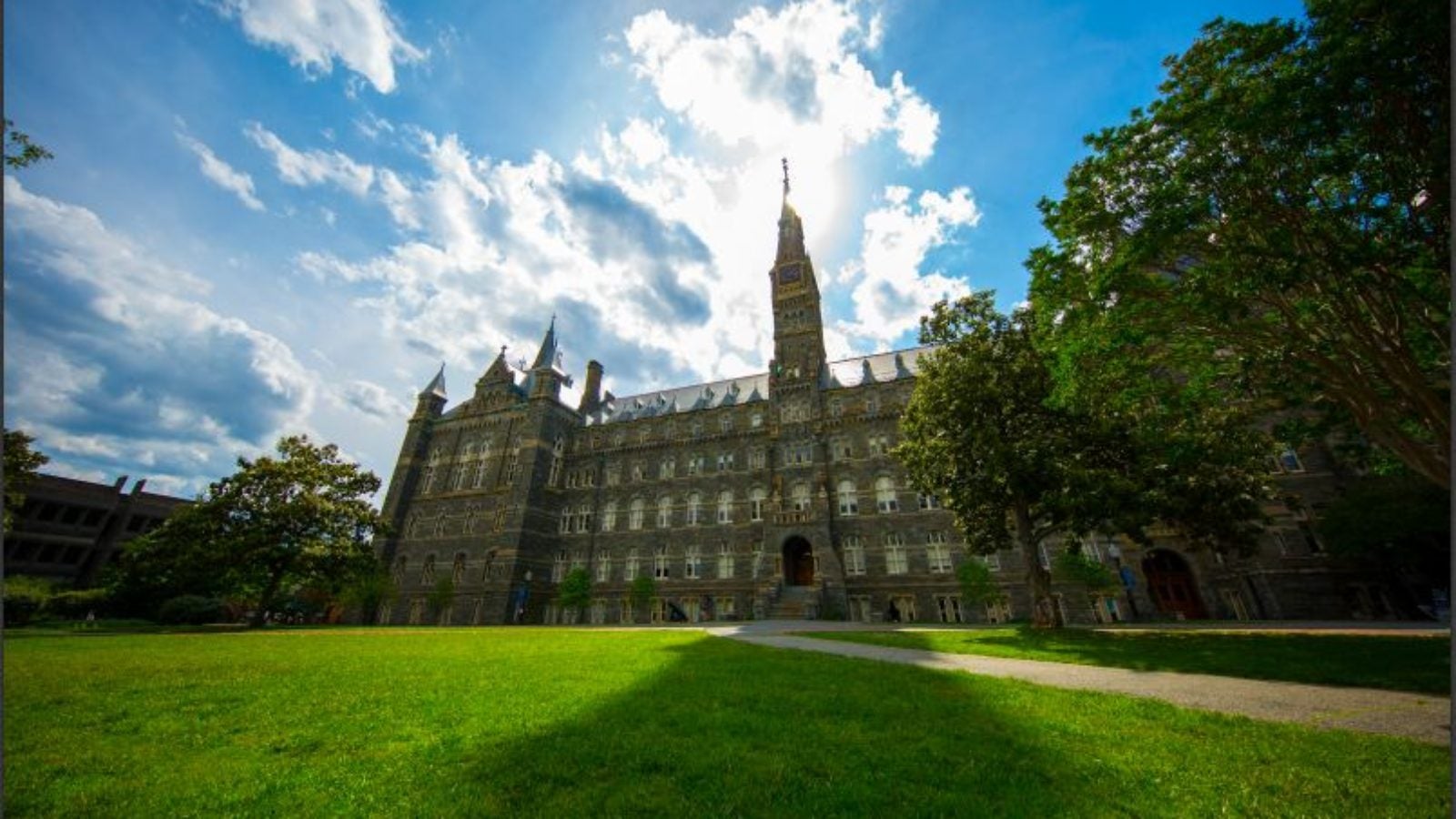 Healy Hall with green lawn and blue sky and fluffy clouds behind it