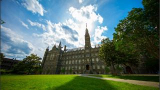 Healy Hall with green lawn and blue sky and fluffy clouds behind it