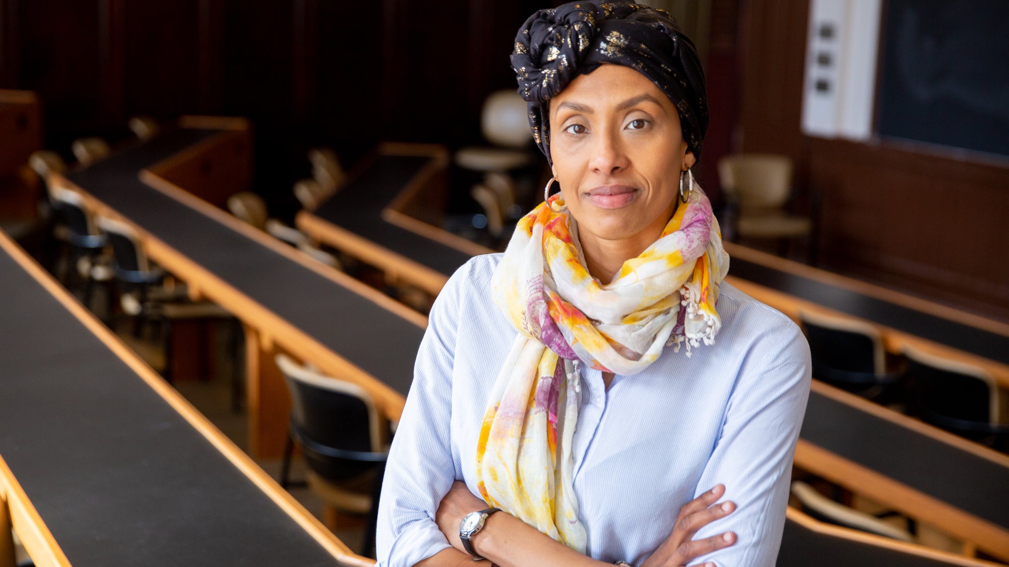 Rahma Maccarone stands with arms folded with an empty classroom in the background.