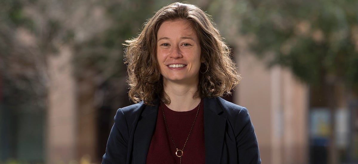 Erika Bullock stands outside with a building and trees in the background.