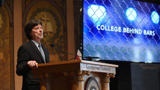 Ken Burns at podium with screen behind him reading College Behind Bars