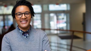 Ijeoma Njaka stands with her arms folded inside a building.