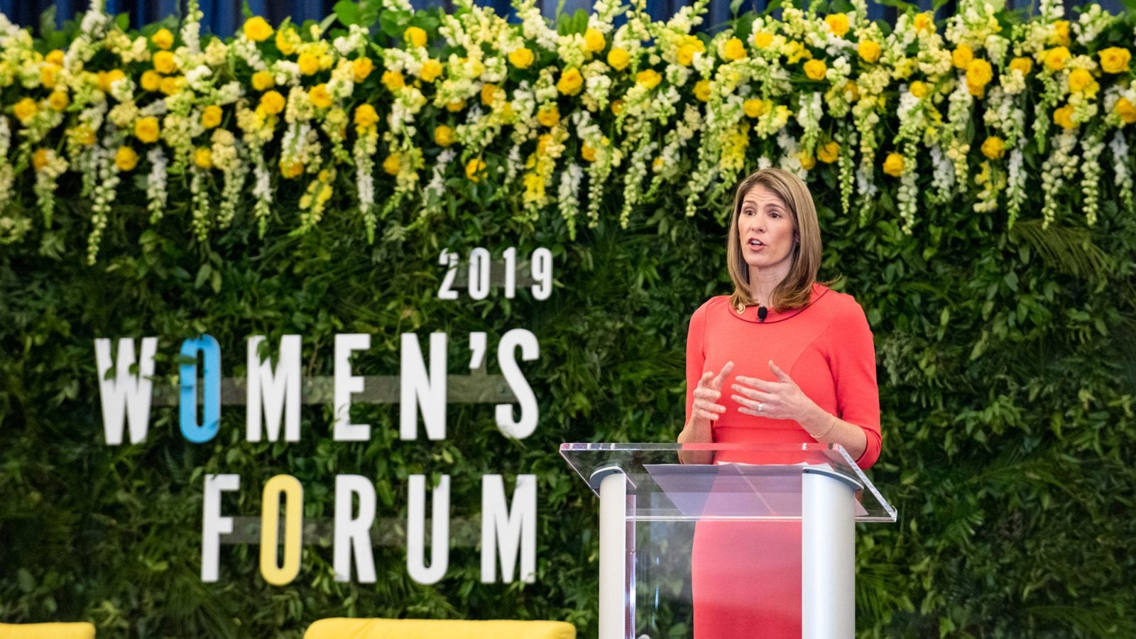 Lori Trahan speaks on stage standing at the microphone with 2019 Women&#039;s Forum signage in the background.