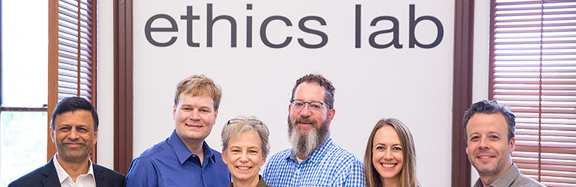 Nitin Vaidya, Ray Essick, Maggie Little, Mark Maloof, Elizabeth Edenberg and Jonathan Healy standing in front of the Ethics Lab sign.