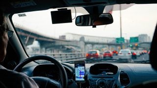 Man driving car with city scene through windshield