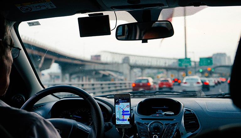 Man driving car with city scene through windshield