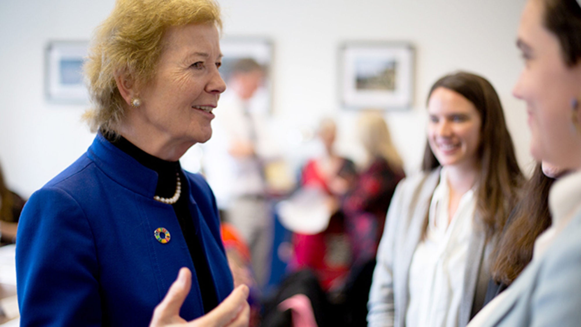 Former Ireland President Mary Robinson stands and talks with a few students with more students in the background