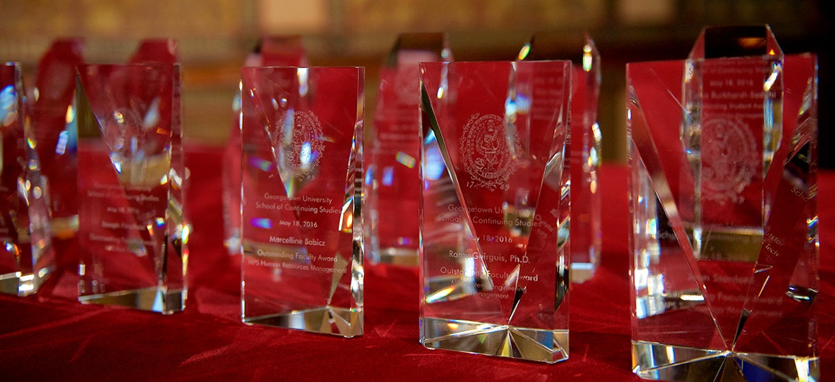 A grouping of glass awards sit on a table covered in red velvet