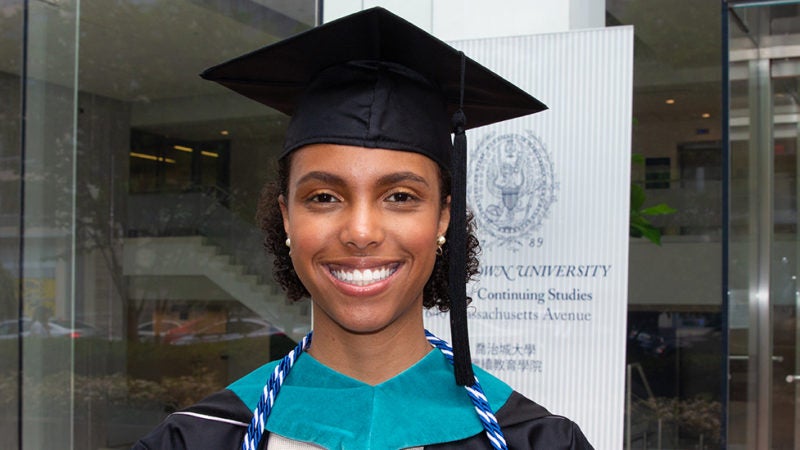 Elizabeth Thomas smiles wearing her graduation cap and gown.