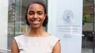 Elizabeth Thomas smile while standing with the School of Continuing Studies entrance in the background.