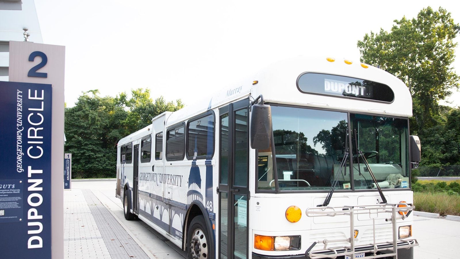 A university GUTS bus shuttle is parked in the bus turnaround.