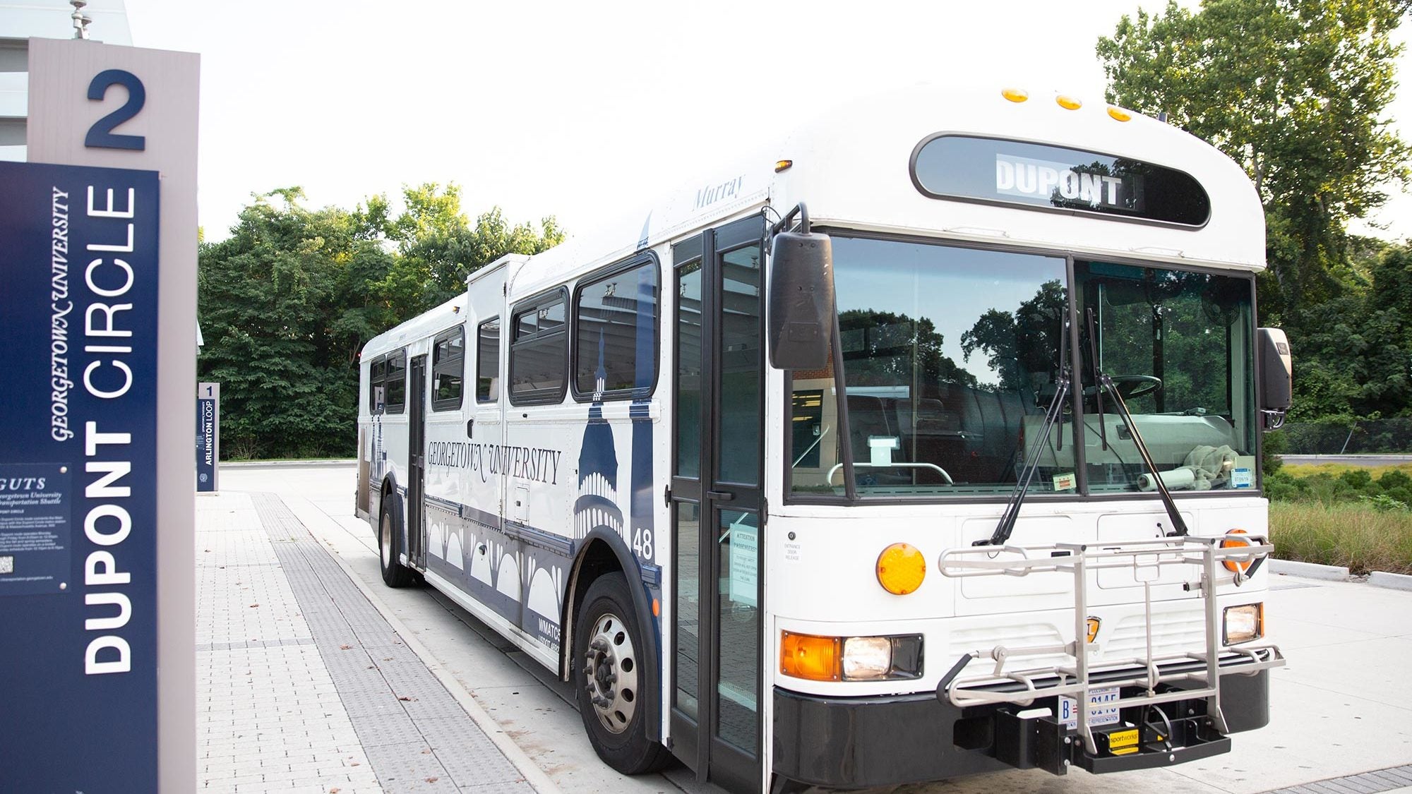 A university GUTS bus shuttle is parked in the bus turnaround.