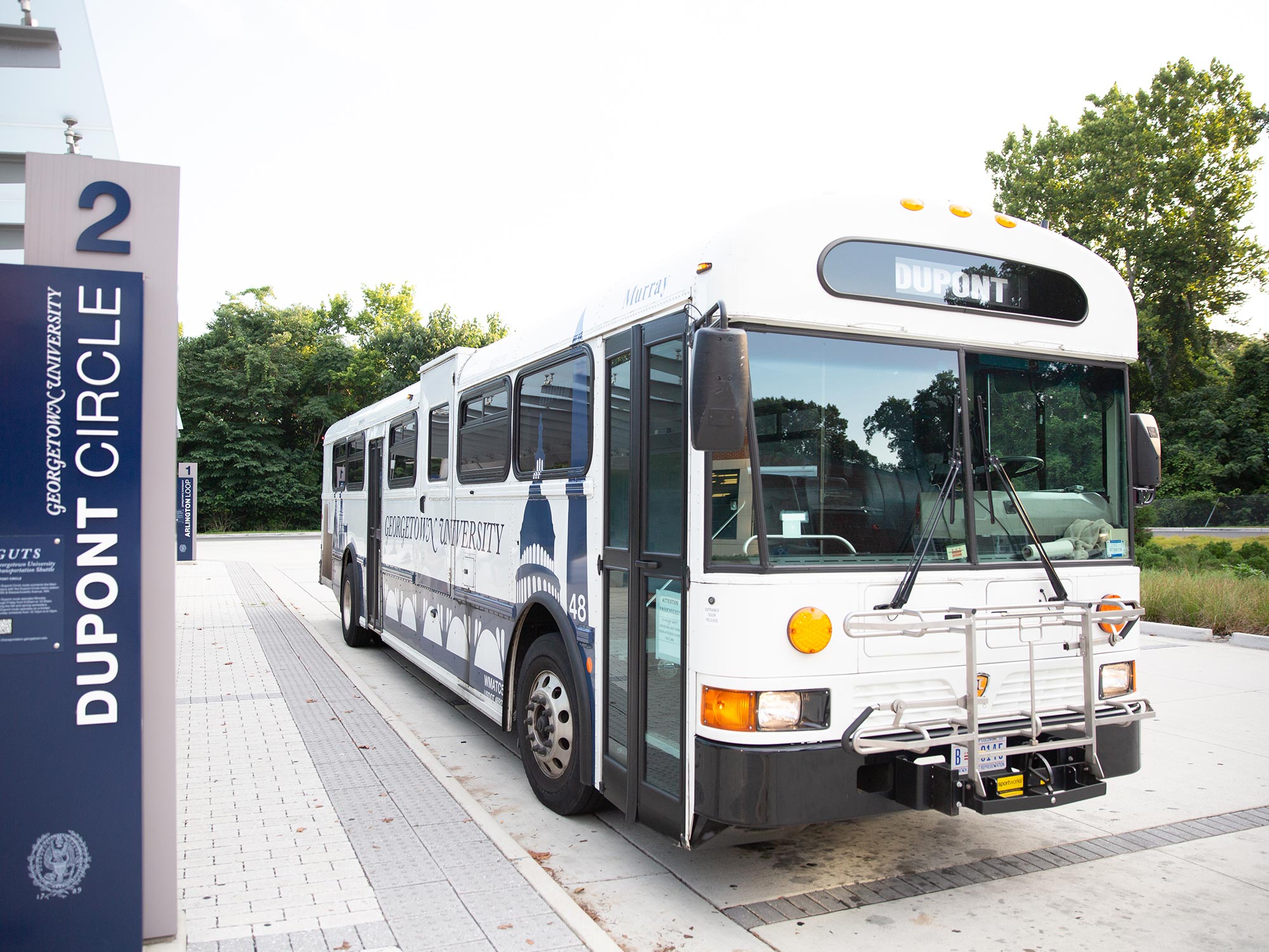 A university GUTS bus shuttle is parked in the bus turnaround.