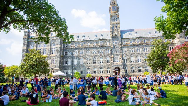 Students sit on the lawn in front of Healy Hall.