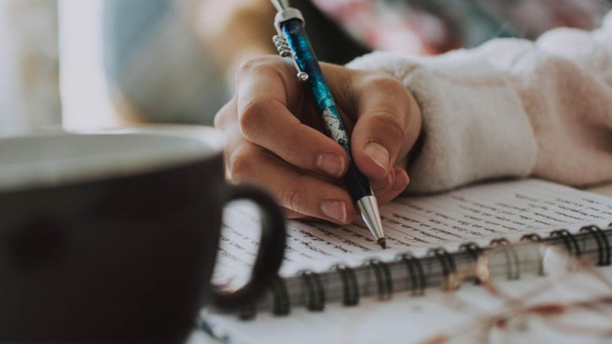 A close-up shot of a person writing in a journal.