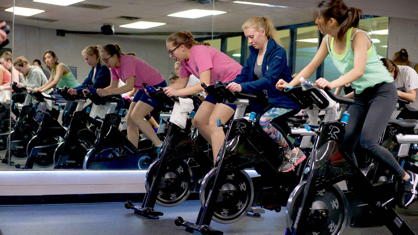 Students spin cylces in a group class in front of a mirror.