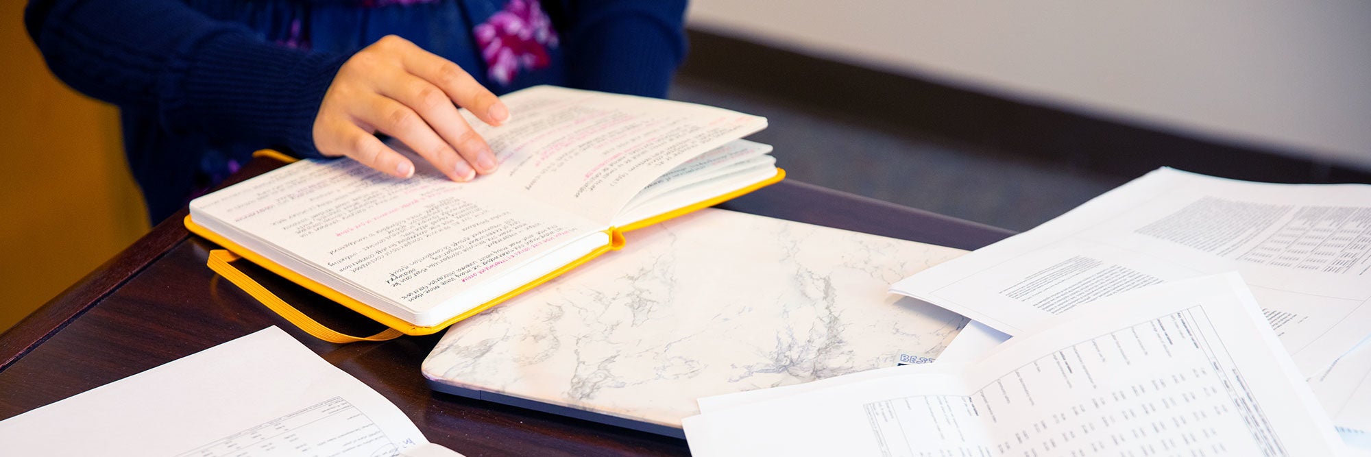 Person&#039;s hand over an open book with notes