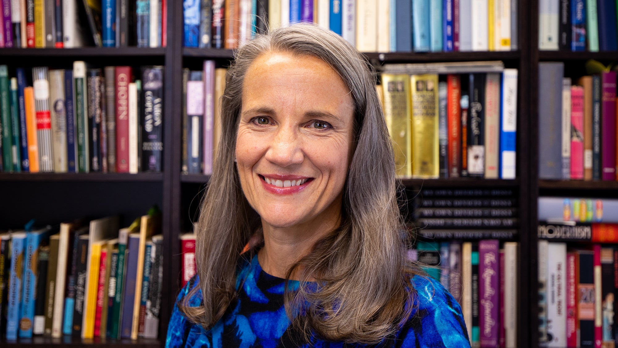 Anna Celenza smiles with shelves of books in the background.