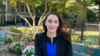 Kristi Pelzel sitting on a bench near flowers with Copley Building behind her