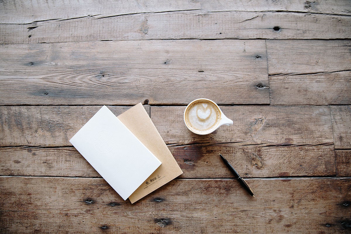 Stationary and coffee sit on a table